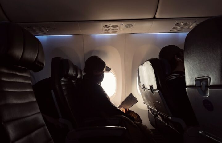 man in black jacket sitting on airplane seat